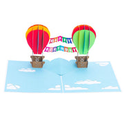 PopLife Pop-Up card features Rainbow colored flying hot air balloons with happy birthday banner in the sky